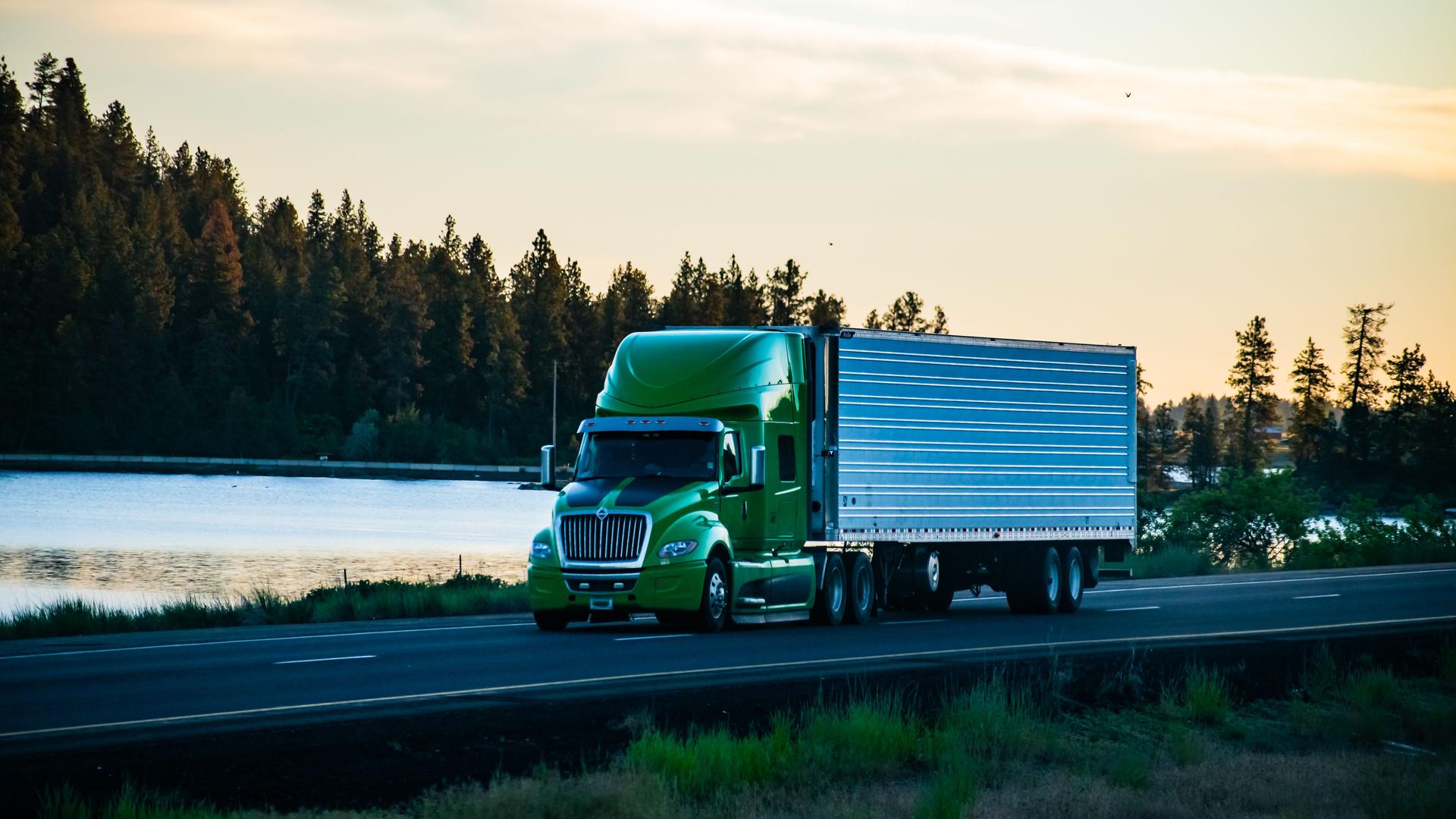 Long-haul semi-truck driving along a scenic stretch of freeway.